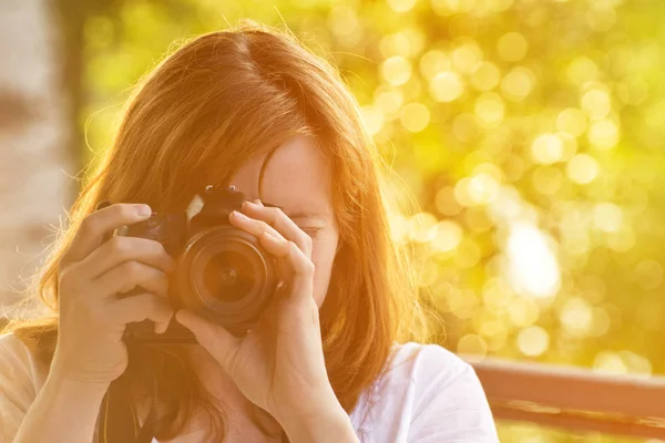 Dívka fotograf fotí na pozadí zeleně. Pohled zepředu — Stock fotografie