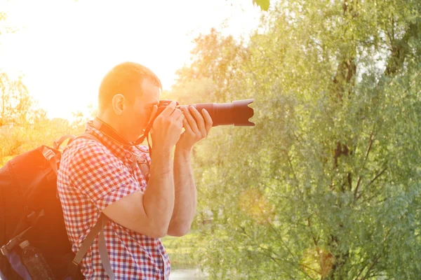 Fotógrafo com câmera SLR e mochila na natureza, vista lateral — Fotografia de Stock