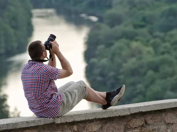 Homem tira fotos de uma colina no fundo da floresta e do rio — Fotografia de Stock