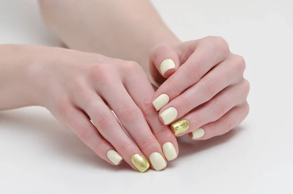 Mãos femininas com manicura, amarelo com cobertura de ouro de pregos. Fundo branco . — Fotografia de Stock