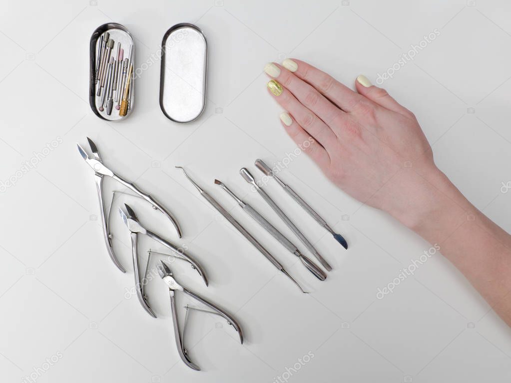 Set of tools for manicure and a female hand. White background.