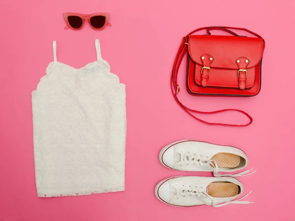 Vit spets upptill, röd handväska, vita sneakers och rosafärgade glasögon. Ljus rosa bakgrund, närbild — Stockfoto