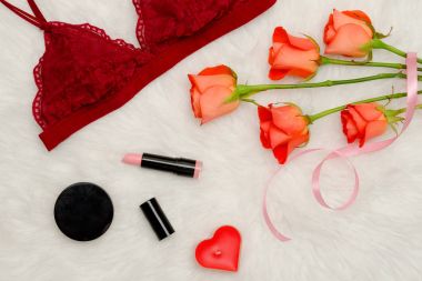 Bordo dantelli büstiyer. Turuncu gül ve kozmetik. Moda kavramı. Üstten Görünüm