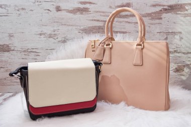 Büyük beyaz bir yapay kürk üzerinde bej ve beyaz-kırmızı çanta. Moda kavramı