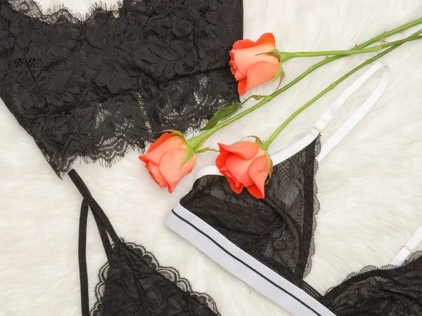 Details black lace bra on the white fur and orange roses. Fashionable concept. Top view. Close-up — Stock Photo, Image