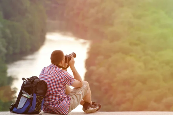 Homem com uma mochila tirando fotos com colina no fundo da floresta e do rio. Tonning. — Fotografia de Stock