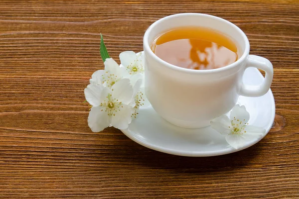 White mug of tea with jasmine on a wooden table. Close up, top view — Stock Photo, Image