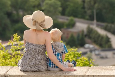 Anne ve oğlu yeşil orman ve köy uzakta arka plan üzerinde oturan