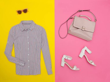 Gömlek küçük bir kafes, el çantası, beyaz ayakkabı ve gözlük. Parlak pembe-sarı arka plan