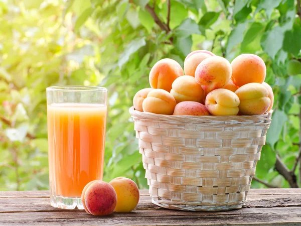 Kayısı bir hasır sepet ve bir bardak meyve suyu Bahçe, güneş ışığı altında
