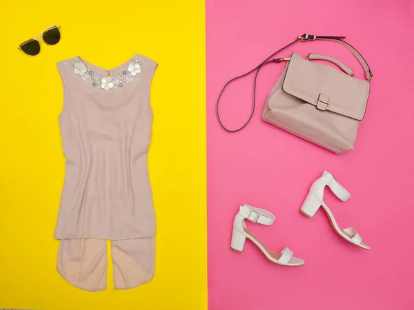 Blouse crème, sac à main, chaussures blanches et lunettes. Fond rose-jaune vif — Photo