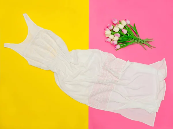 Белое длинное платье и букет тюльпанов на ярком розово-желтом фоне — стоковое фото