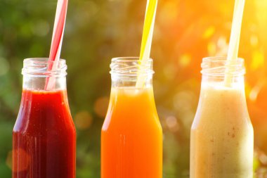 Üç şişe suyu payet bir arka planda yeşil, yaz, güneş ışığı ile. Yakın çekim