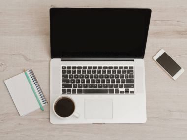 Bir fincan kahve ve bir dizüstü bilgisayar, dizüstü bilgisayar açık, smartphone. Hafif ahşap arka plan, üstten görünüm