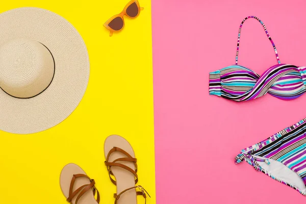 Beach kavramı. Kadın şapka, sandalet, Mayo, güneş gözlüğü. Sarı, pembe bir arka plan, üstten görünüm