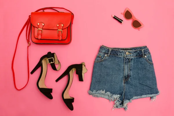 Denim shorts, schoenen en een rood handtas, helder roze achtergrond. Modieuze concept — Stockfoto