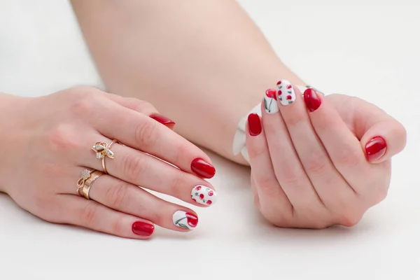 Female hands with manicure, red nail polish, drawing with cherries. White background.