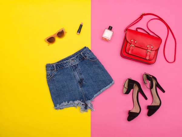 Calções de ganga, sapatos e uma bolsa vermelha, fundo amarelo brilhante e rosa. Conceito na moda — Fotografia de Stock