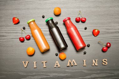 Üç şişe suyu, meyve ve yazıt vitaminler siyah ahşap zemin, gıda kavramı ile