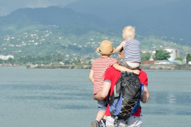 Babası iki oğlu ile sahilde hazır. Arkadan görüntülemek