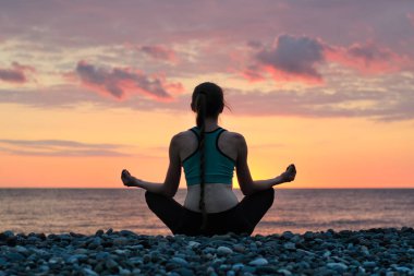 Lotus pozisyonu Sahilde meditasyon kadın. Arkadan, gün batımı görüntülemek