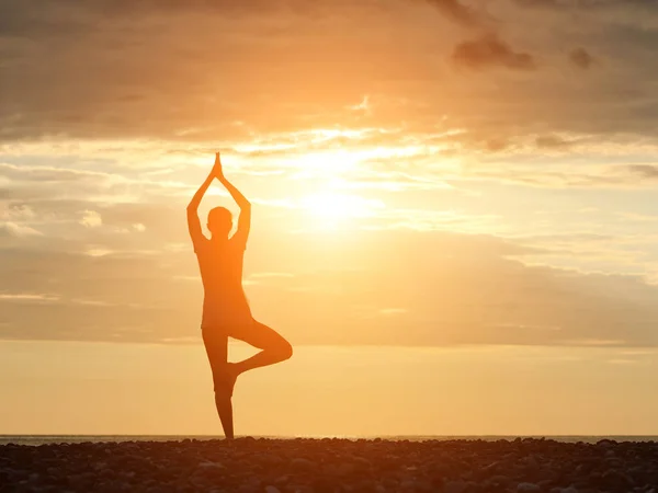 Flicka vid solnedgången praktisera yoga på stranden, siluett — Stockfoto