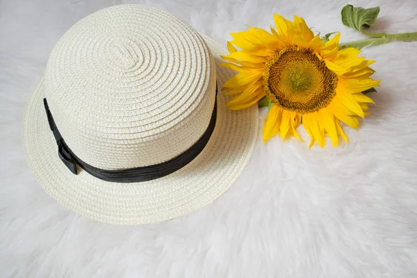 Солом'яний капелюх зі стрічкою та соняшником на білому хутрі. Модна концепція, вид зверху — стокове фото