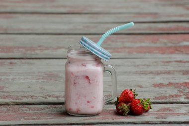 Kupa ile yoğurt ve çilek kırmızı arka plan vintage ahşap plakalar üzerinde