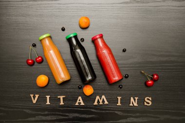 Üç şişe suyu, meyve ve yazıt vitaminler siyah ahşap zemin, gıda kavramı ile