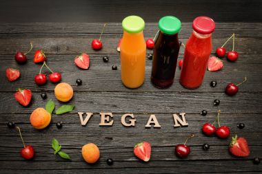 Üç şişe suyu, meyve ve yazıt vegan koyu ahşap zemin, gıda kavramı ile