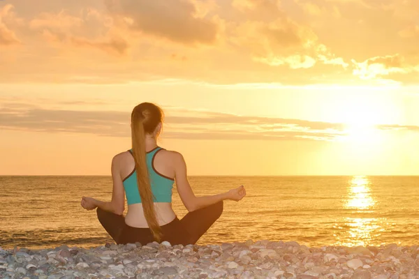 Kvinna som mediterar på stranden i lotusställning. Visa från baksidan, solnedgång — Stockfoto