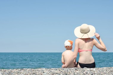 Anne ve oğlu sahilde oturan ve deniz hayranım. Arkadan görüntülemek