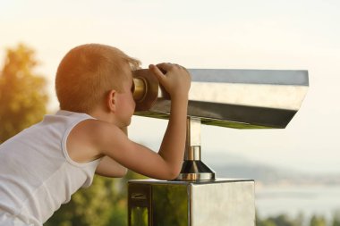 Çocuk büyük dürbün görünüyor. Gökyüzü arka plan üzerinde