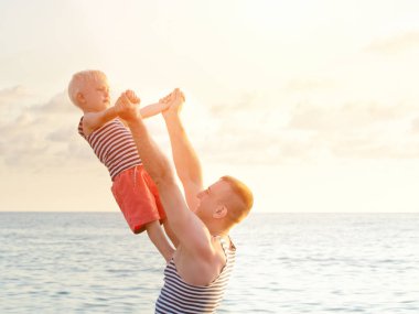 Dade uzanmış oğlu sahil üzerinde eller tutuyor. Arkadan görüntülemek