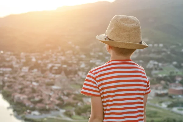 Αγόρι στο καπέλο που βλέπουν την πόλη από ύψος. Οπίσθια όψη, ώρα το βράδυ — Φωτογραφία Αρχείου
