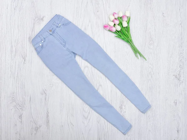 Mavi jeans ve Lale bir buket. Moda kavramı. Ahşap arka plan.