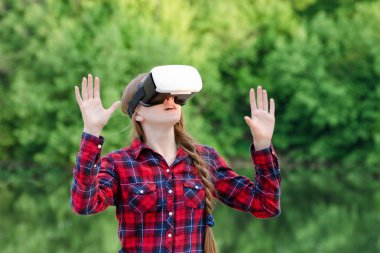 Sanal gerçeklik gözlüklü kız, ellerini yeşil arka planı tutuyor