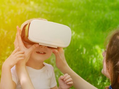 Anne oğlu gözlüklerini arka planı yeşil çim sanal gerçekliğin düzeltir