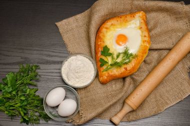 Khachapuri yas, un, yumurta ve maydanoz siyah tablo üzerinde yumurta ile