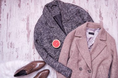 İki yün ceket, kahverengi deri ayakkabılar beyaz kürk, yarım greyfurt, ahşap arka plan. Moda kavramı. Üstten Görünüm