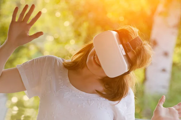 Mädchen im Helm der virtuellen Realität vor dem Hintergrund der Natur. Sonnenlicht — Stockfoto