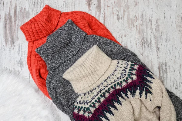 Três suéteres quentes de pescoço em um fundo de madeira. Conceito de moda . — Fotografia de Stock