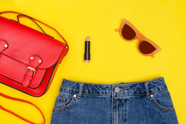 빨간 핸드백, 데님 반바지, 선글라스와 립스틱. 밝은 노란색 배경. 세련 된 개념 — 스톡 사진