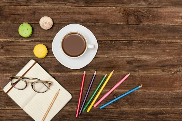 Kahve kupa, bademli kurabiye, renkli kalemler ve ahşap bir zemin üzerine gözlük ile not etmek. Üstten Görünüm, boşaltmak
