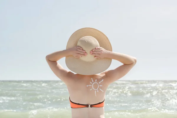 Chica con las manos detrás de la cabeza, pintado de sol en la espalda. Mar en el fondo — Foto de Stock