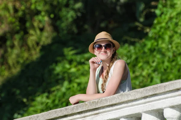 Fille dans un chapeau et des lunettes de soleil fermé profiter de la nature. Journée ensoleillée, parc — Photo
