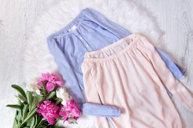 Sönük bir omuz ve bir buket peonies ile mavi ve pembe bluz. Moda kavramı, beyaz kürk arka planda
