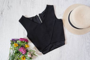 Siyah top. Şapka ve kır çiçekleri buketi. Moda kavramı, üstten görünüm