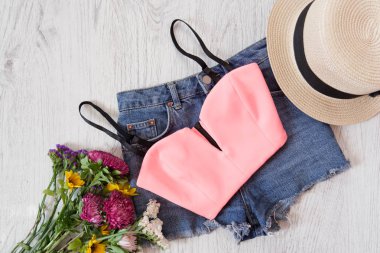 Pembe top, kot şort, şapka ve kır çiçekleri buketi. Moda kavramı