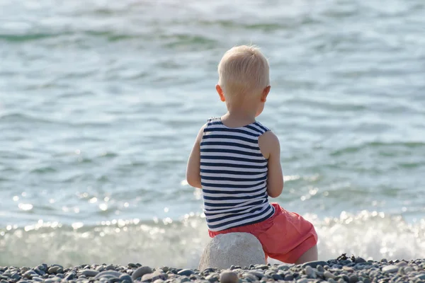 Çizgili tişört sahilde oturan çocuk. Arkadan Görünüm